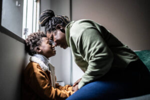 Mother and son touching their heads at home, offering emotional support while coping with anxiety.
