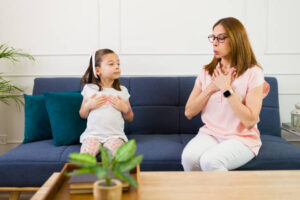 A mother helping her little girl calm down with some breathing exercises in a relaxed environment. Helping children cope with anxiety in therapy sessions with a child therapist