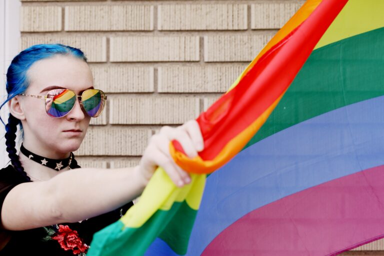 Photo of an LGBTQ teen holding a rainbow flag that represents the LGBTQ community. If your teen is struggling to fit in as an LGBTQ member, discover how therapy for LGBTQ youth in Macon, GA can help your teen begin to fit in and cope with their emotions.