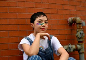 Photo of a girl sitting on the ground against a brick wall with a rainbow pattern across her face. Is your teen struggling to manage their mental health? Discover how teen counseling in Macon, GA can help provide your teen with support.