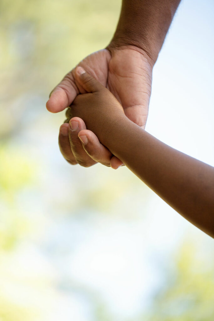 Image of a parent holding a child's hand outside. Discover how online therapy in Utah can help your child begin effectively managing their emotions and behaviors.