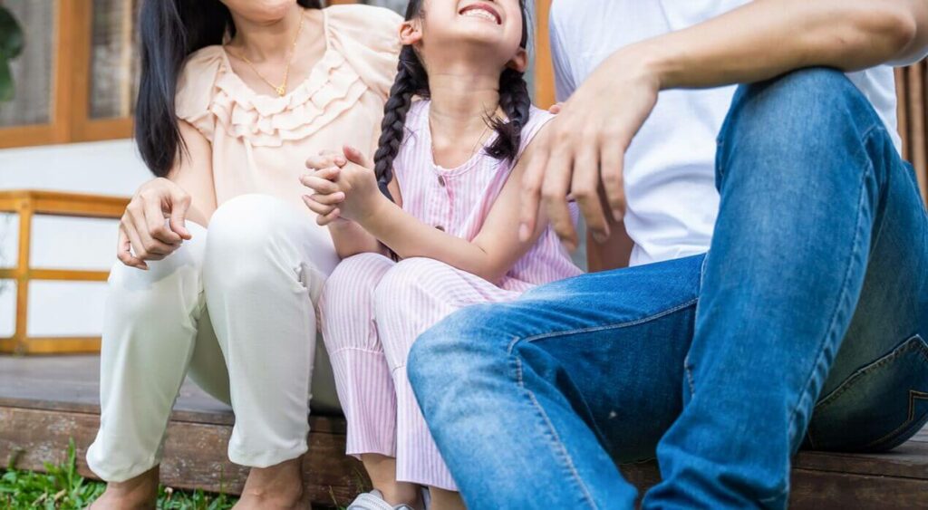 Image of a smiling family sitting outside looking at each other. Discover how online therapy in Massachusetts can help your family overcome their trauma, anxiety, depression, and more at The Comfy Place!