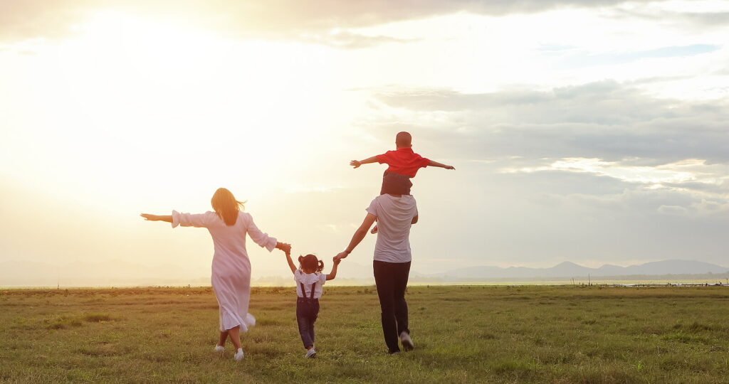 Image of a happy family walking through a field toward the sunset. Learn to help your family overcome their struggles with the help of online therapy in Maine.