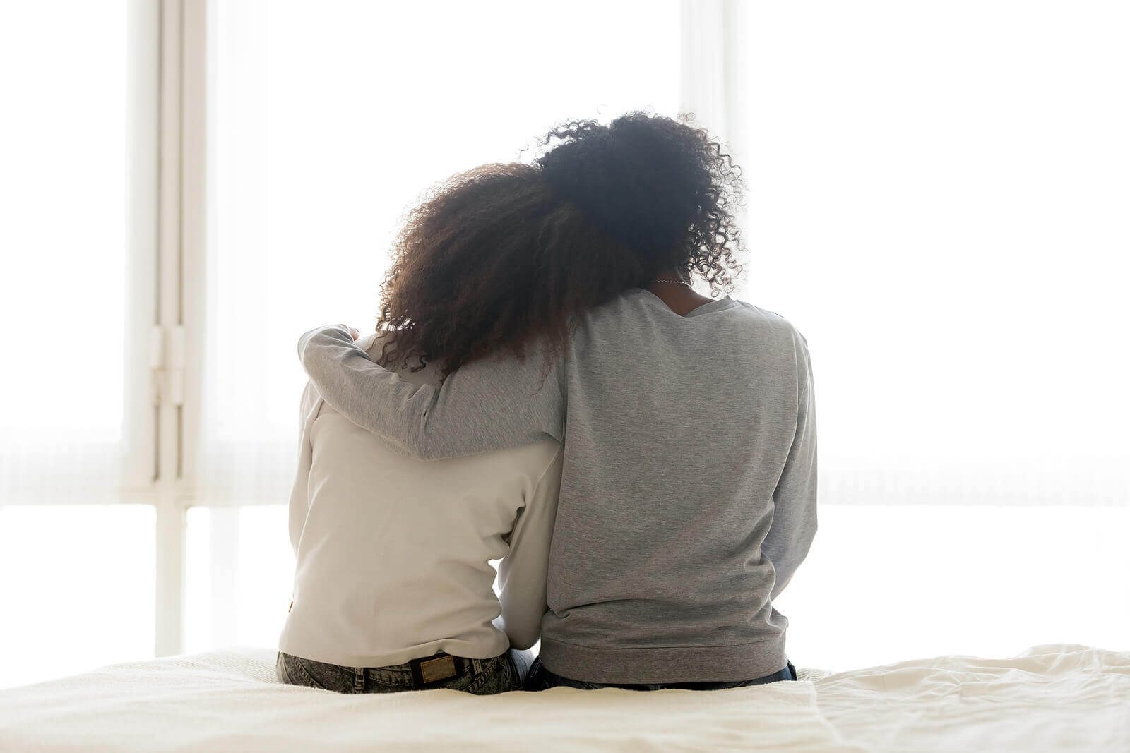 Image of a mother and daughter sitting on a bed hugging. With the help of teen counseling in Macon, GA your teen can overcome the anxiety that may be affecting their mental health from social media.