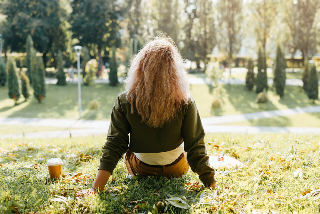 Photo of a woman sitting in the grass during the day. Are you suffering from trauma symptoms and are unable to manage them? With trauma therapy in Macon, GA you can begin learning the coping skills to manage your trauma in a supportive space.