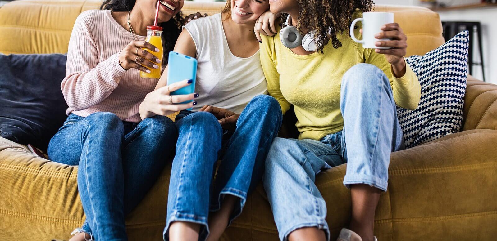 Image of a happy group of teen girls sitting on a couch looking at a cell phone. Uncover how social media may be affecting your teen, and find them support with teen counseling in Macon, GA.