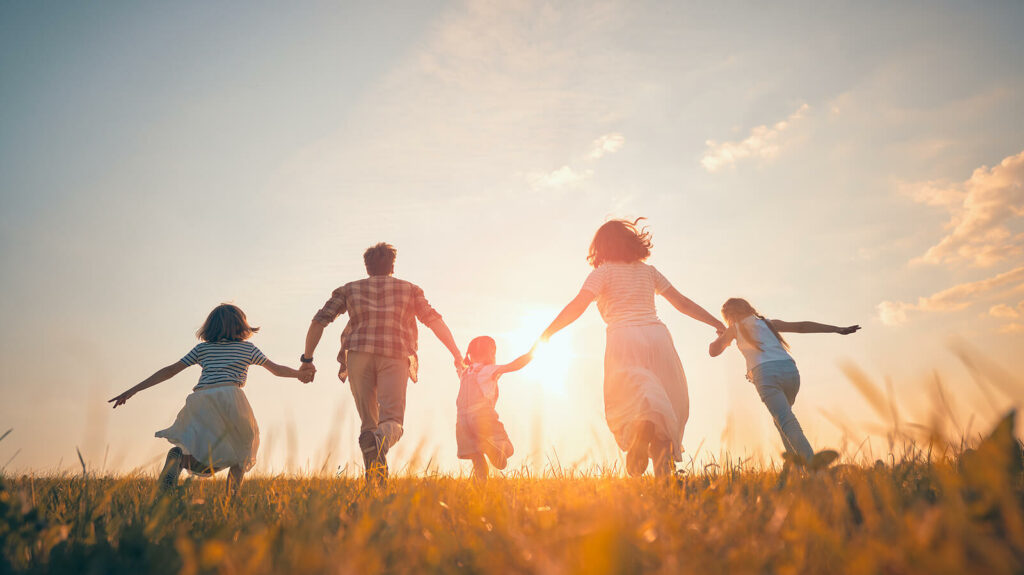 Image of a happy family running through a field at sunset. Looking for therapy for your anxiety? Learn how online therapy in Utah can help you begin overcoming your anxiety symptoms in healthy ways.