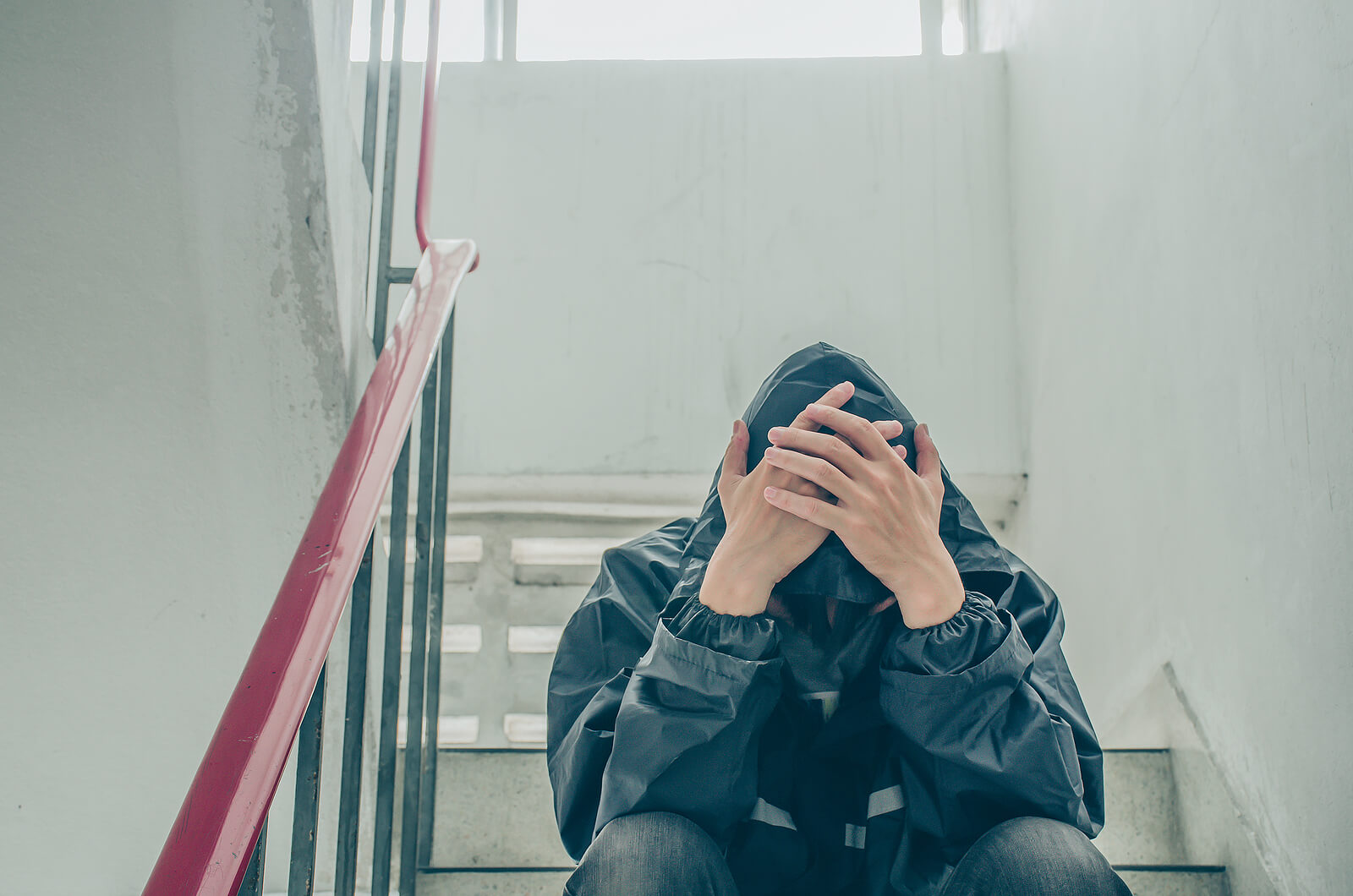 Image of a young teen boy sitting on stairs covering his head with his hands. Help your teen learn to cope with their anxiety with the help of teen counseling in Macon, GA.