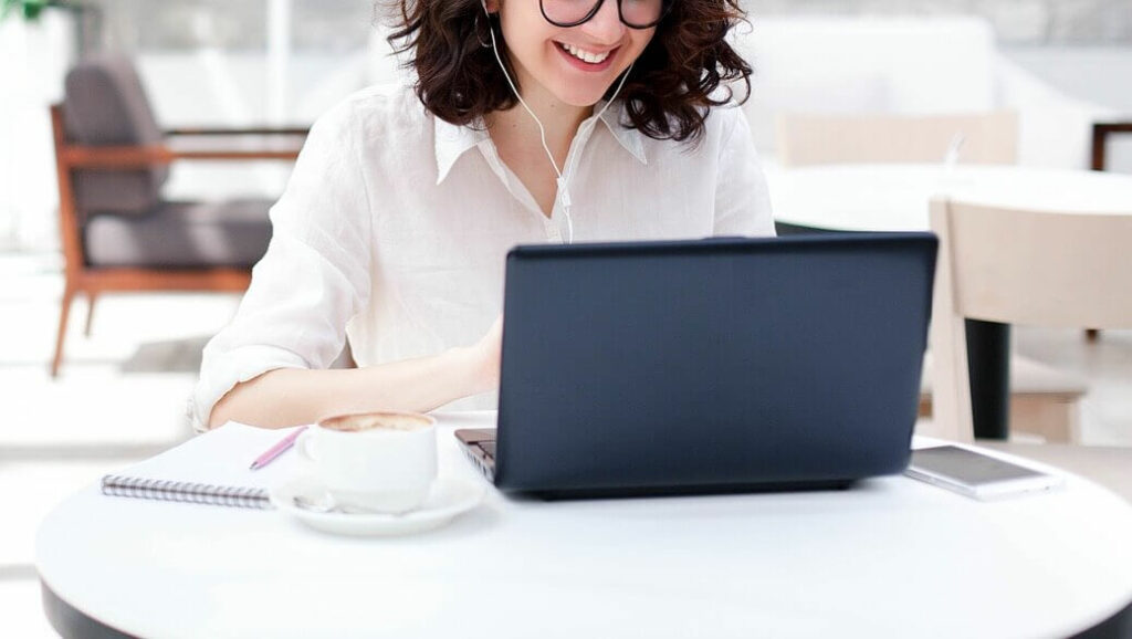 Image of a young woman smiling and looking at a laptop. Discover how online therapy in Maine can help you and your family manage your symtpoms.
