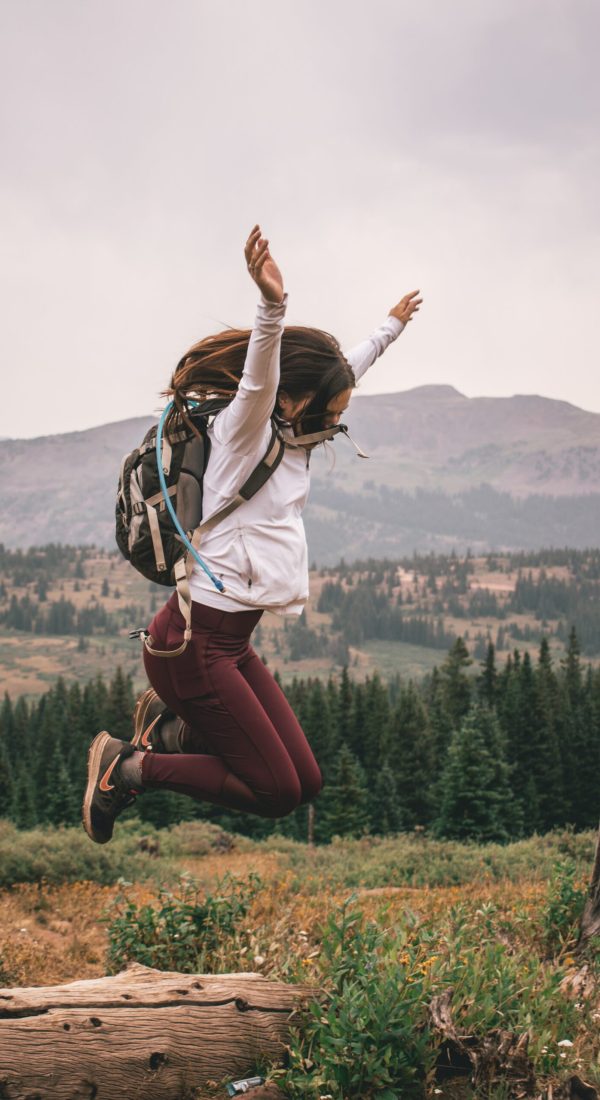 Photo of a woman jumping in the air while on a hike in the woods. Learn to heal from past wounds with the help of IFS therapy in Macon, GA.