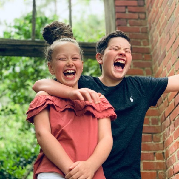 Photo of a boy with his arm around a girl's shoulder both laughing and smiling. With child therapy in Alpharetta, GA your child can receive the support they may need when it comes to managing their emotions and overcoming their struggles.