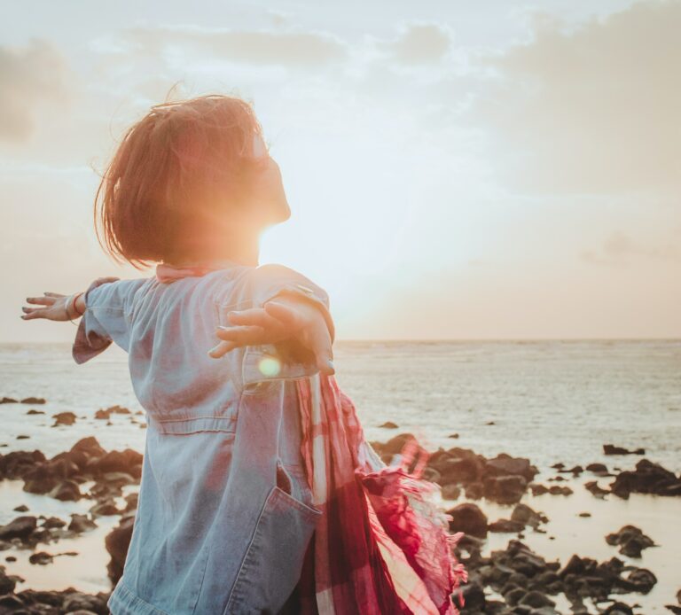 Photo of a woman running toward the beach while the sun sets. Learn to effectively manage your trauma symptoms with the help of somatic experiencing therapy in Macon, GA.