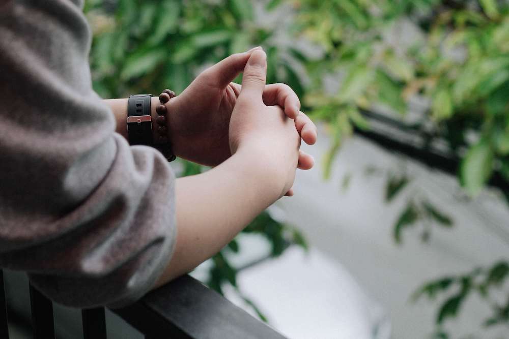 Photo of someone clasping their hands together and leaning over a balcony. Learn to effectively cope with your PTSD in healhty ways with the help of a therapist in PTSD therapy in Macon, GA.