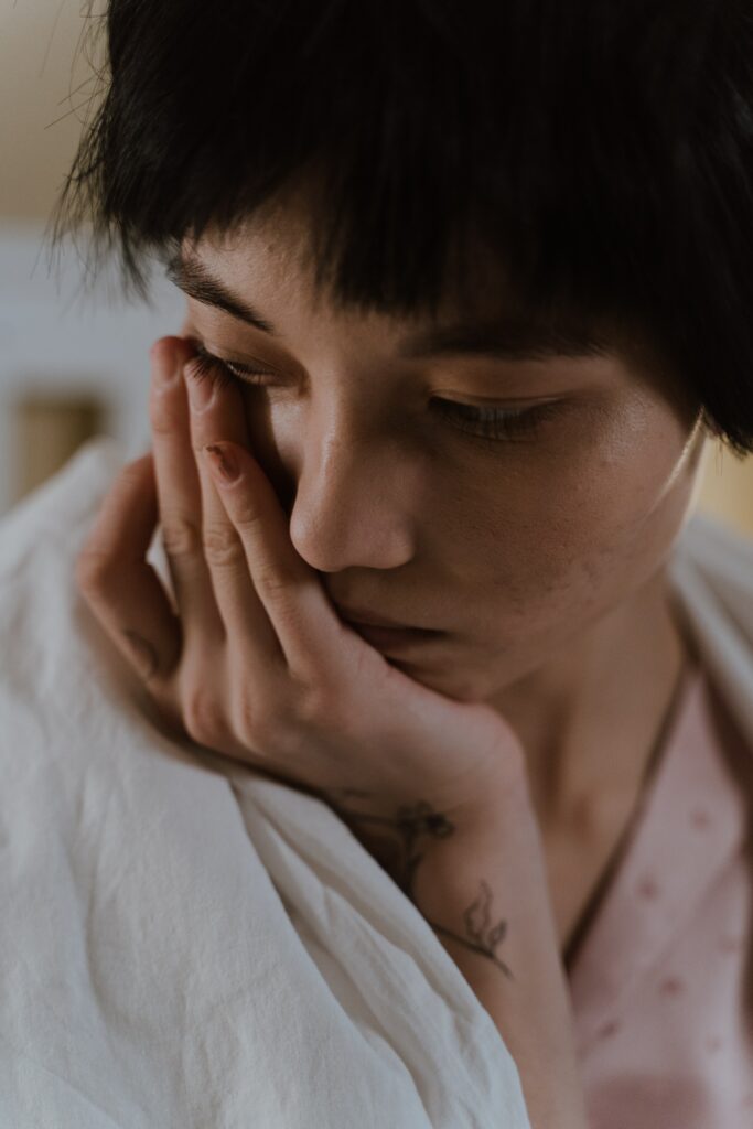 Photo of a woman resting her hand on her face and looking down. Discover how somatic experiencing therapy in Macon, GA can help you combat your trauma symptoms.