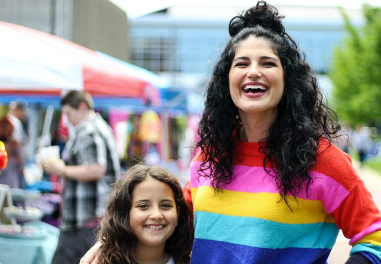 Photo of a mother wearing a rainbow shirt and child standing in a street smiling. Discover how therapy for LGBTQ youth in Macon, GA can help your child begin to manage their emotions as a an LGBTQ member. Find support with an affirming LGBTQ therapist.