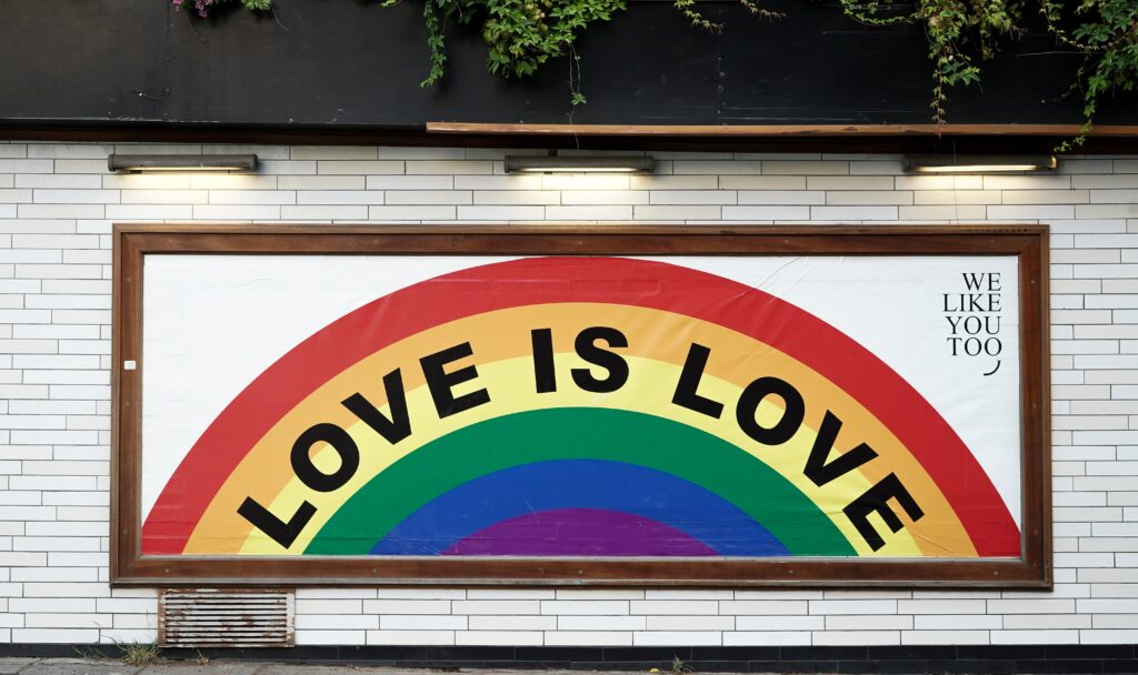 Photo of a sign with a rainbow that reads love is love. Are experieicing trauma as a LGBTQ+ member? Discover how LGBTQ affirming therapy in Macon, GA can help you explore your emotions and how to cope in a healthy way.